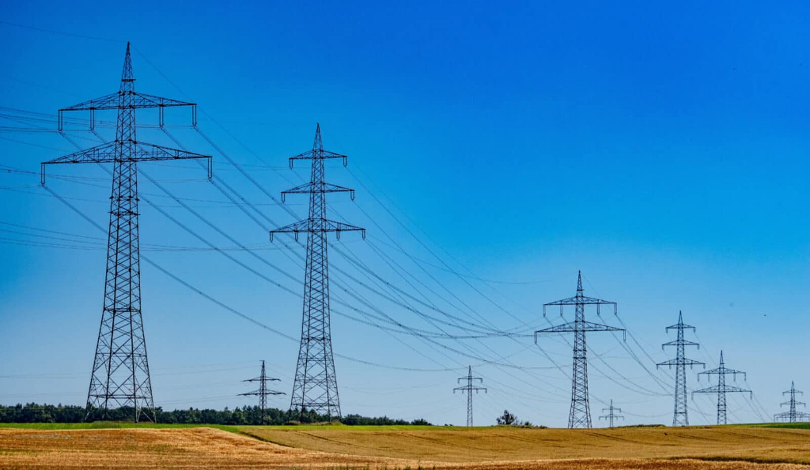 electrical transmission towers across open field under blue sky